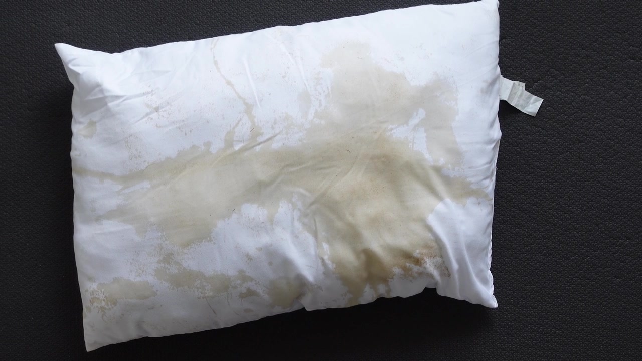 Almohada blanca manchada sobre una superficie oscura texturizada
