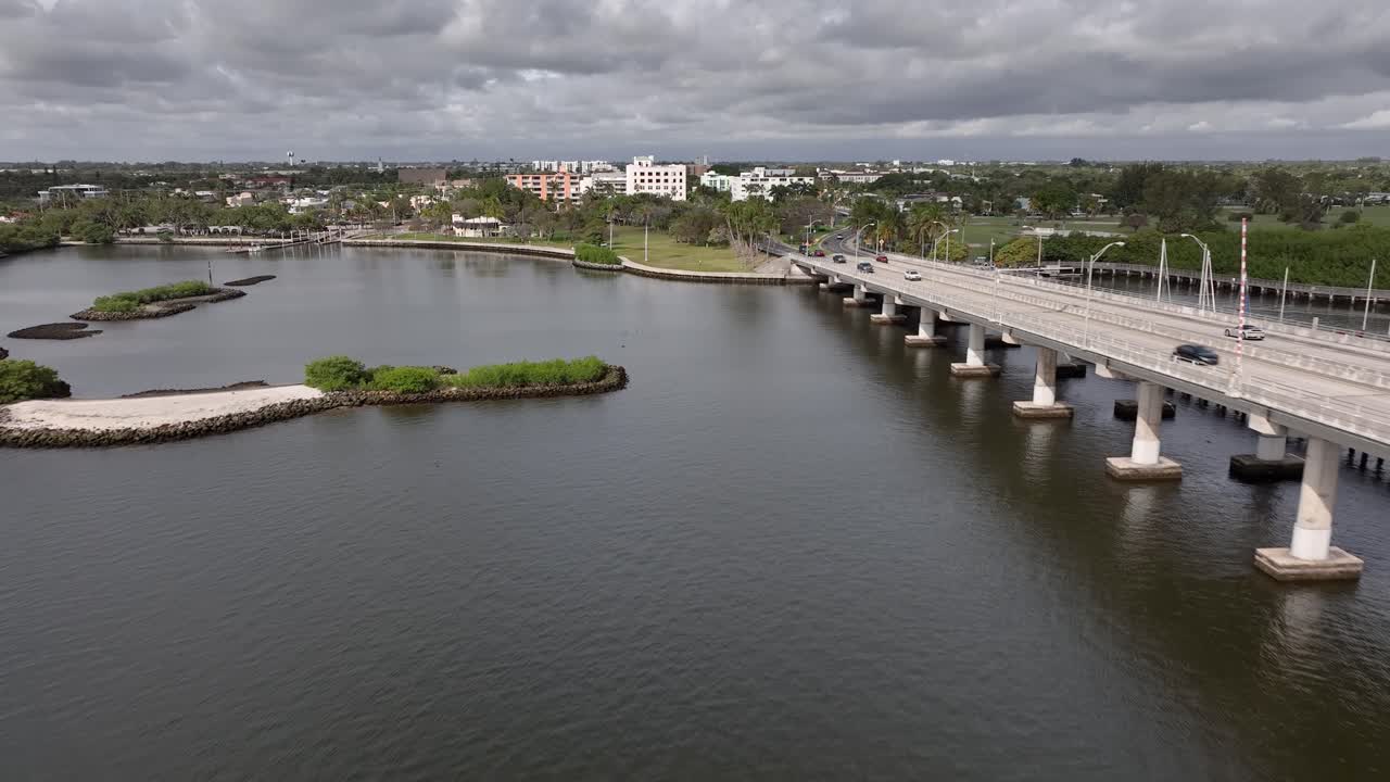 Drone flying west over the intracoastal waterway next to the drawbridge and approaching Lake Worth Beach Florida on a cloudy overcast day