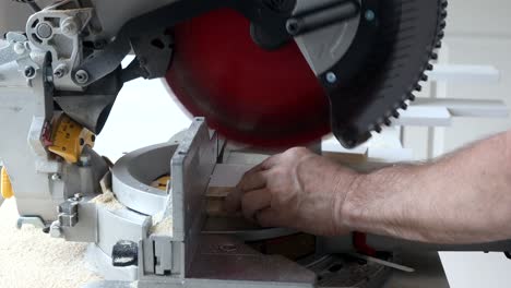 worker cuts wood baseboard on the power miter saw new home before installing