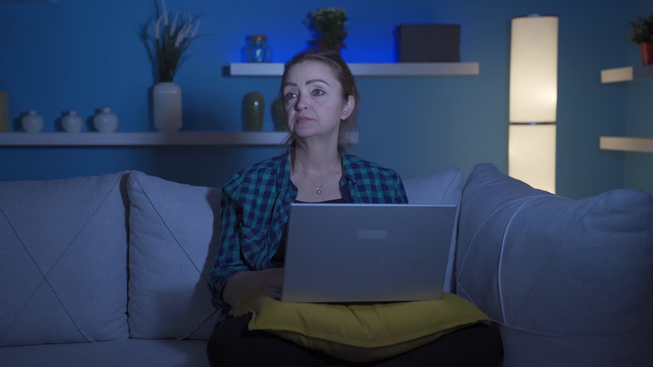 женщина устает, используя компьютер ночью.