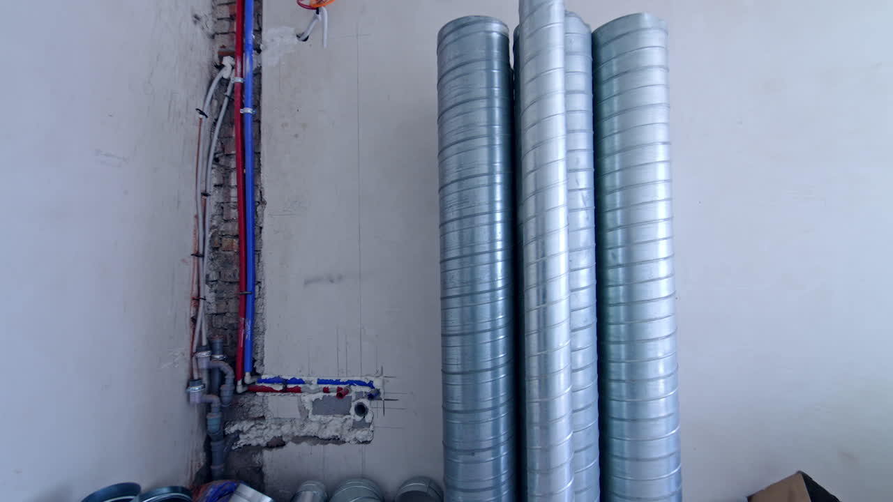 Metal pipes of diverse width stand at the bare wall. Reconstruction of an old building.