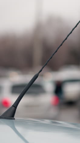 una vista borrosa cercana de automóviles que pasan y otros automóviles estacionados, capturada desde la perspectiva de una antena de automóvil, con luz borrosa vista desde la distancia