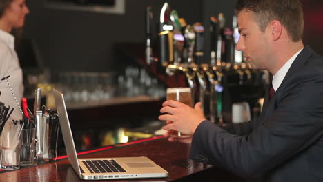 businessman working on his laptop while having a beer
