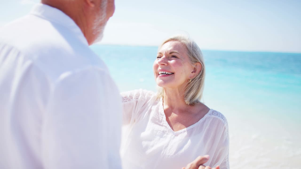 влюбленная пенсионерская кавказская пара танцует вместе на пляже.