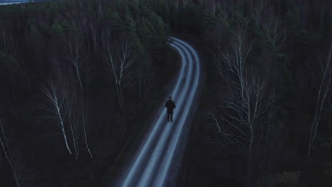 man walking on a road in a dark forest