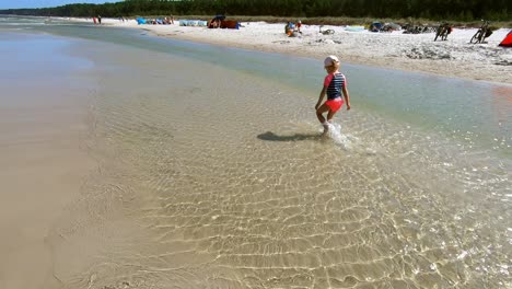 Niña-Caminando-Lentamente-Salpicando-Agua-En-La-Playa