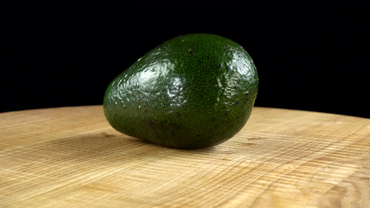 Avocado su sfondo nero. Tagliere in movimento.