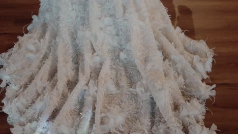 close-up of the lace train of a wedding dress spread out beautifully on a wooden floor, highlighting its delicate details