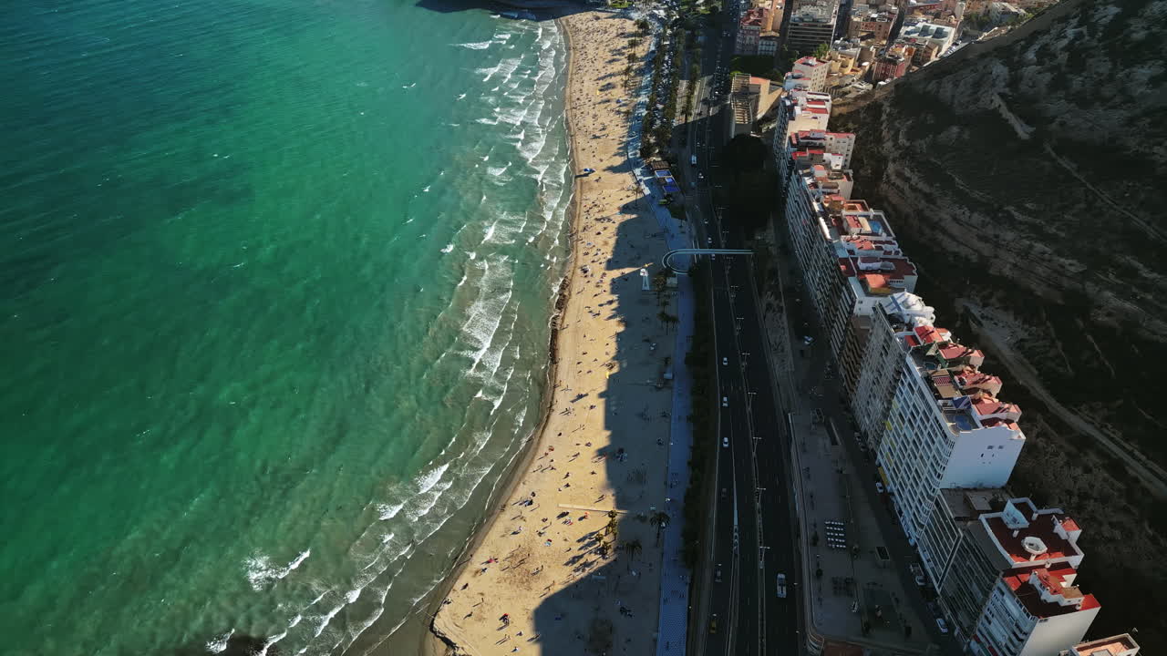 Aerial drone view of cars moving along the coastline in Alicante, Spain in daylight