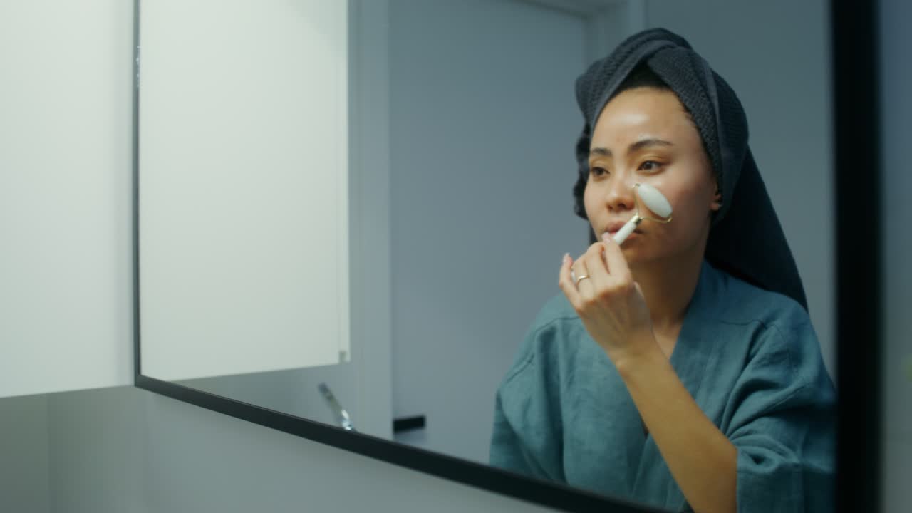 Woman using facial roller in bathroom