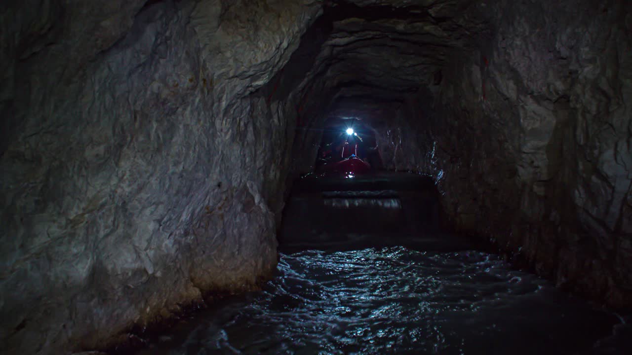 Front view of people on kayak approaching in dark mine tunnel