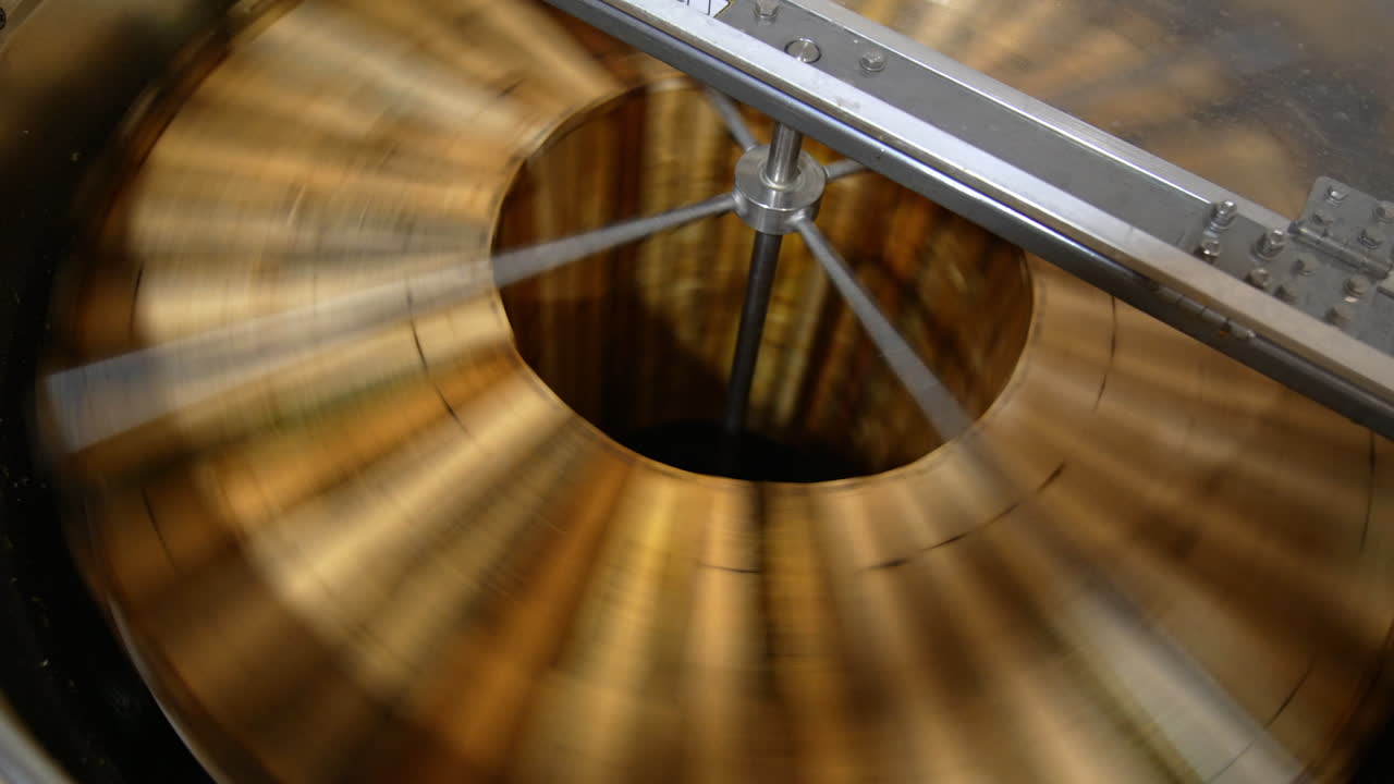Fresh organic honey being extracted from wooden frames. Centrifuge machine rotating quickly for harvesting honey at apiary.