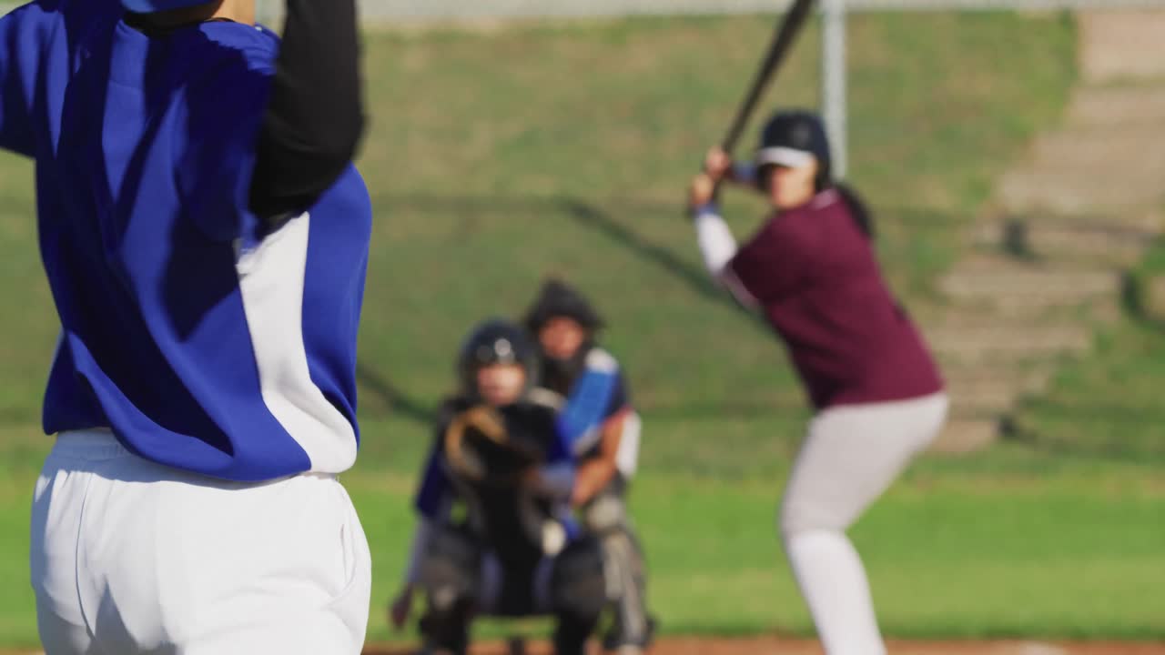 Gruppo eterogeneo di giocatrici di baseball in azione sul campo, palla lanciata presa dal ricevitore.