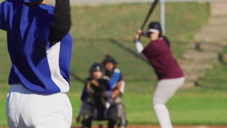 diverse group of female baseball players in action on the field, pitched ball caught by catcher