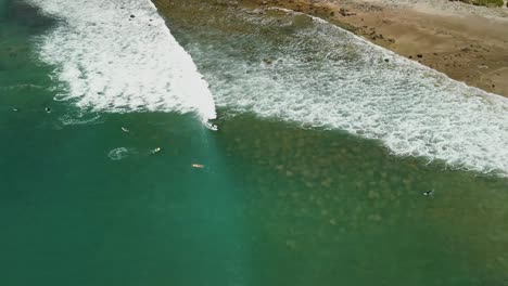 Surfer-catching-wave-above-shallow-reef-close-to-beach