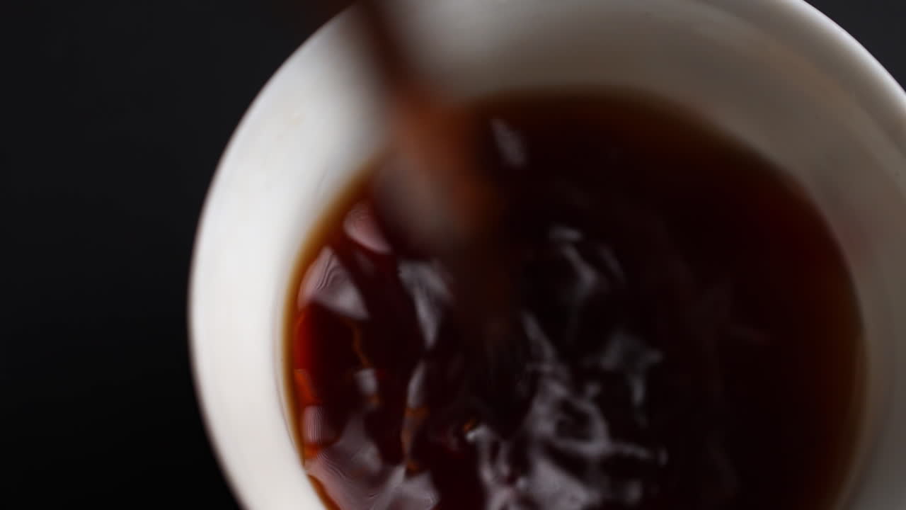 검은 차를  컵에 부어 넣는 것