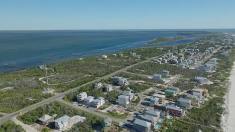 High-aerial-flyover-of-Cape-San-Blas,-Florida-following-vehicles-along-main-road