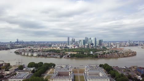 an elevating aerial drone view of isle of dogs from greenwich observatory park during a cloudy grey weather