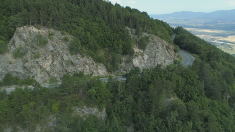 black suv driving at mountain highway with beautiful forest around the road