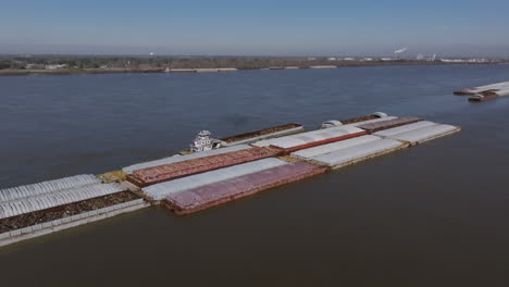 Imágenes-Aéreas-Amplias-Centradas-En-Un-Remolcador-Que-Empuja-Una-Barcaza-Llena-De-Chatarra-En-Baton-Rouge,-Luisiana.