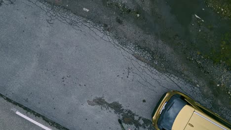 Exiting-the-golden-car-in-Lofoten-Norway-and-hand-catching-the-drone-that-was-flying-above-the-street