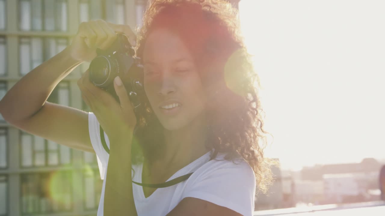 Fashionable young woman on urban rooftop taking photos