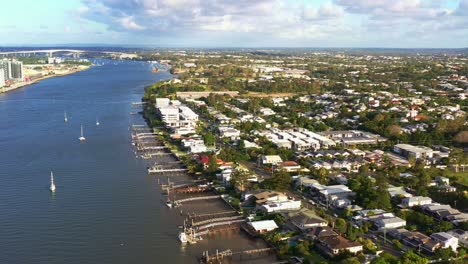vista aérea inclinada hacia abajo a lo largo del banco capturando el barrio residencial de bulimba, casas junto al río con rampa y embarcadero, barcos amarrados en el agua, brisbane, queensland, australia