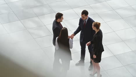 top view of group of workers dressed in elegant clothes greet each other in the hall of the office building