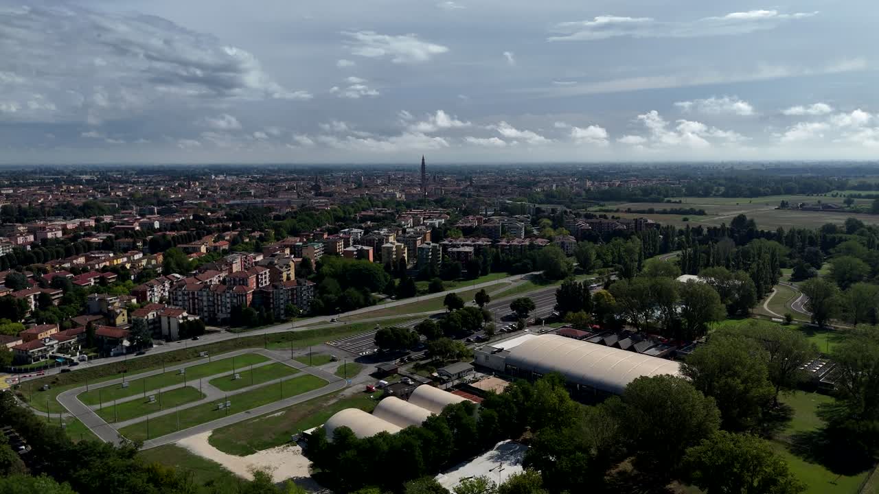 Establishing Aerial View of Cremona Lombardy Italy with Rooftops Greenery and Distant Torrazzo Tower Under a Cloudy Sky