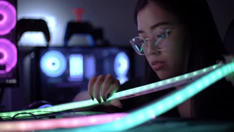 a focused gamer enhancing her setup: illuminating rgb lights and gaming gear in a darkened room for the ultimate experience