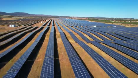 expansive solar farm under clear blue skies: aerial view showcasing rows of solar panels efficiently harnessing renewable energy in a rural landscape
