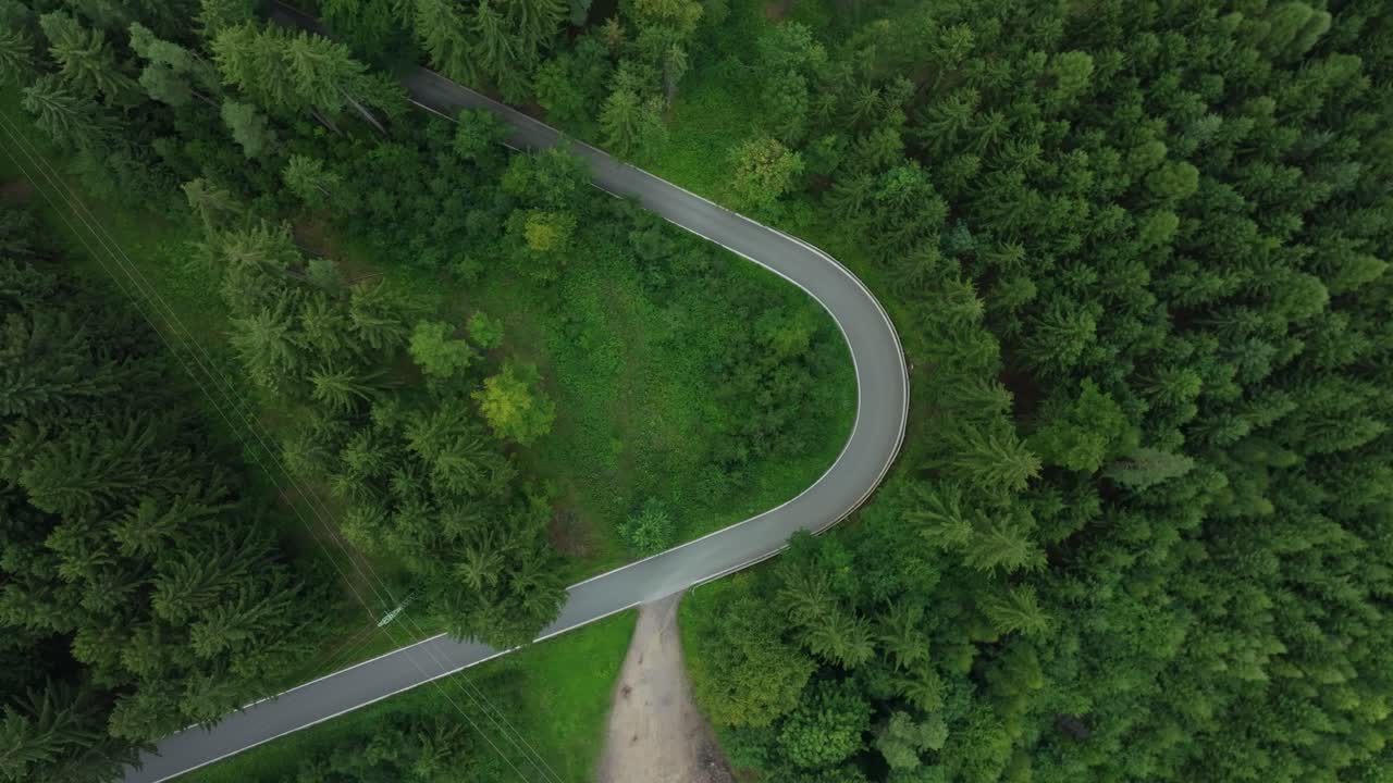 Road with a sharp bend in the middle of the forest. Downhill from a drone view