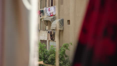 Peeking-between-hanging-clothes-at-residential-apartment-house,-Cairo