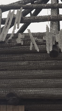 remains of roof of wooden house after fire. log cabin under cloudy sky. medieval building made of large logs. old traditional architectural object