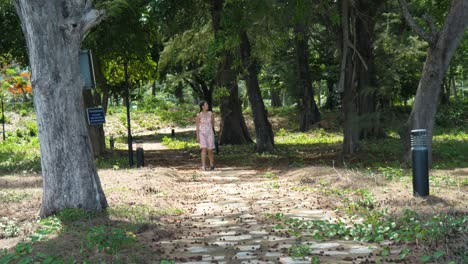 mujer con un vestido ligero caminando por un camino del bosque en la isla de con dao, vietnam