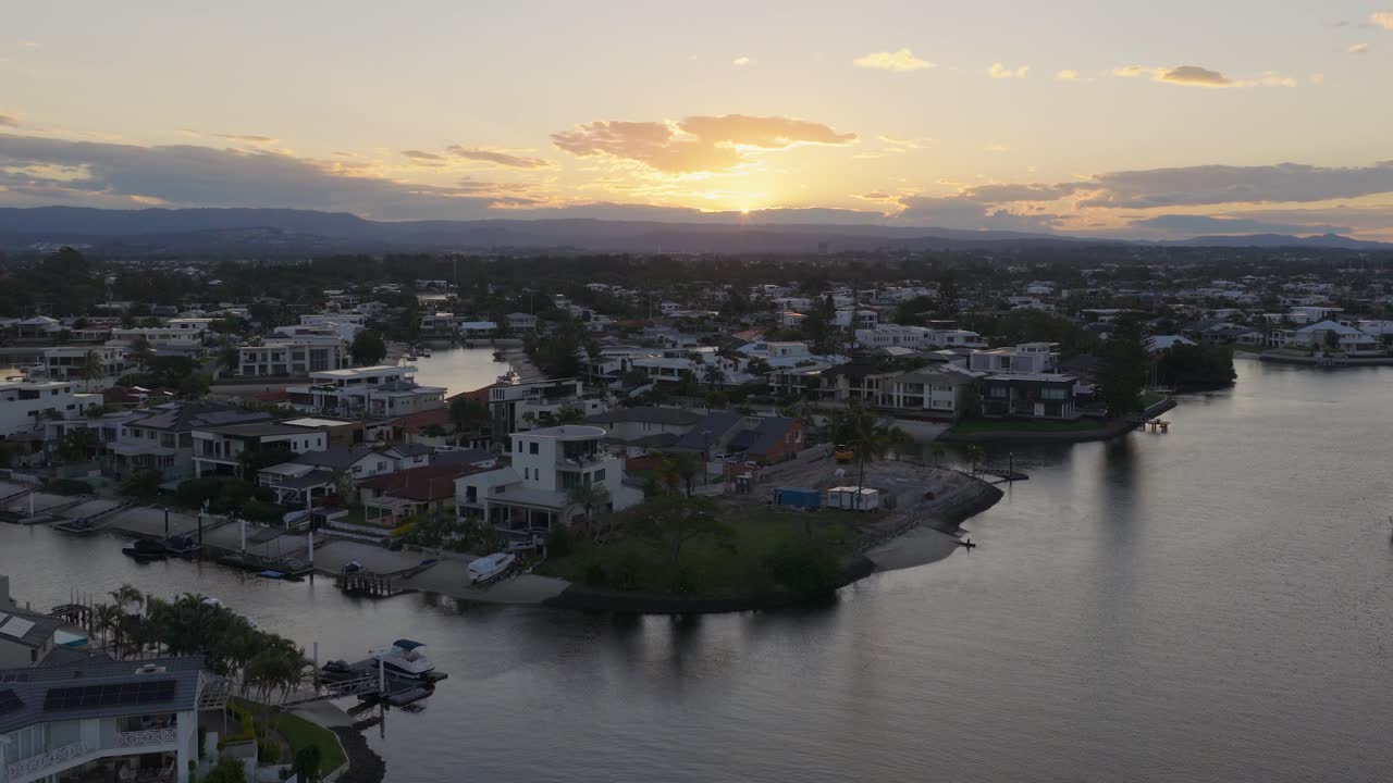 Drone footage captures Gold Coast canals at sunset, highlighting serene waters and residential areas with warm, fading light