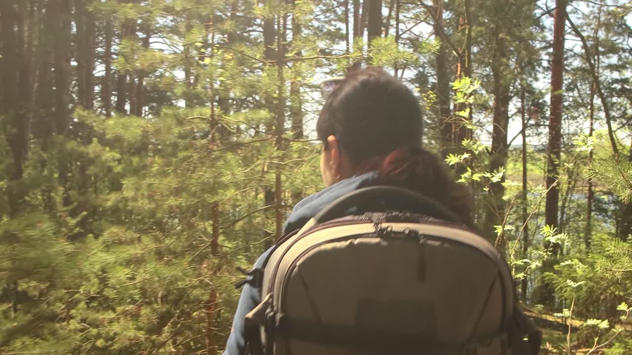 mujer caminando con una mochila de senderismo en el bosque verde de primavera