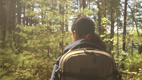 Hiking-woman-walk-with-a-hiking-backpack-in-spring-green-forest