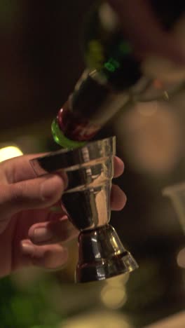 close-up of bartender pouring alcoholic drink into measuring cup preparing cocktail