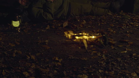 man sleeping by campfire in forest at night