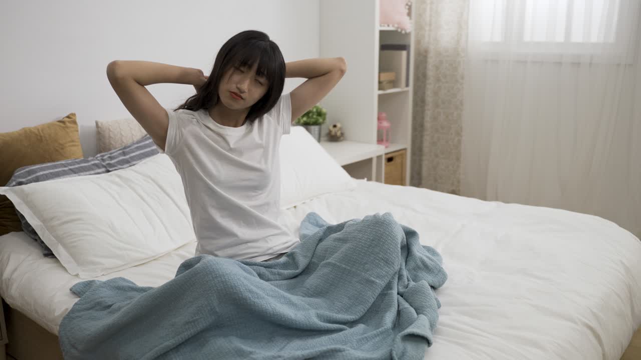 신선한 아시아 여성의 초상화, 그녀의 몸을 어 앉아 밝은 집 내부에서 아침에 일어난 후 침대에서 나온다.