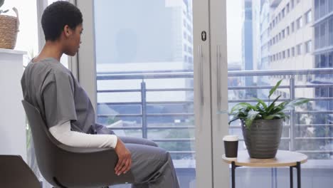 tired african american female doctor sitting in hospital waiting room, slow motion