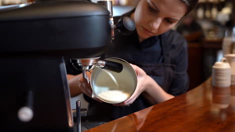 a barista steaming milk with an espresso machine