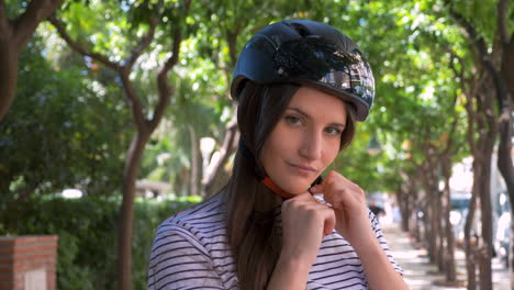 portrait of a beautiful young woman taking off her helmet while smiling at camera