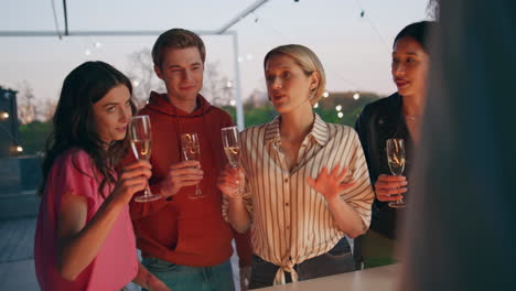 diverse youngsters toasting drinks in sunset bar terrace. friends celebrating