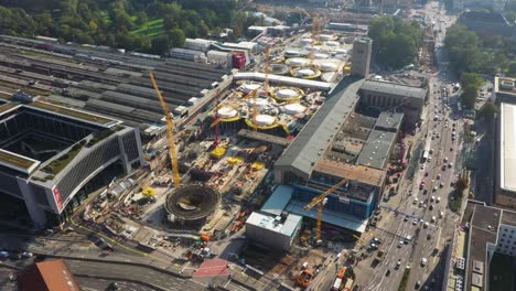 aerial flying above huge railroads, intersection and construction site of main train station stuttgart s21 with cranes and construction worker in stuttgart, germany