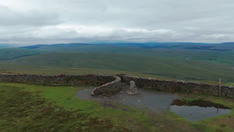 expansive green hill landscape with stone wall under cloudy sky