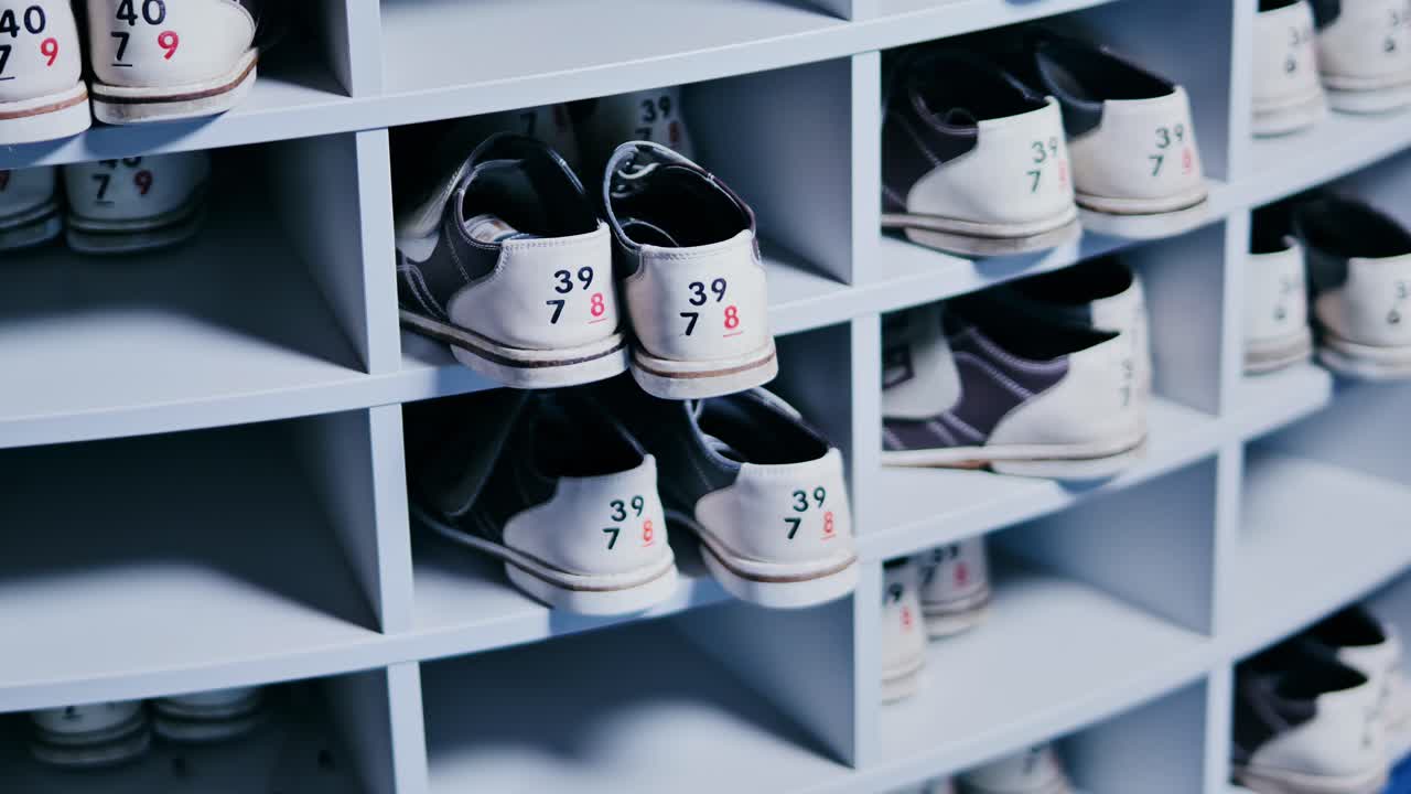 Labeled bowling shoes neatly arranged in semicircle shelf inside bowling center