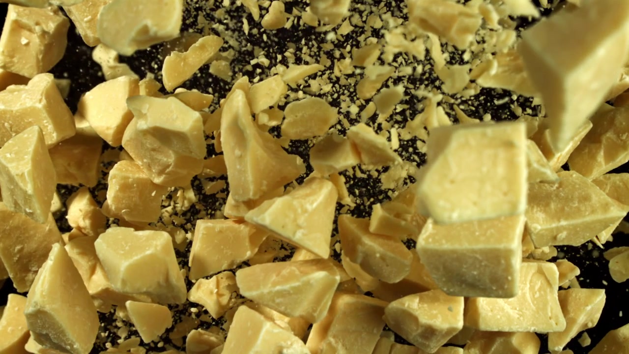 Movimento super rallentato di pezzi e scaglie di burro di cacao che si disperdono