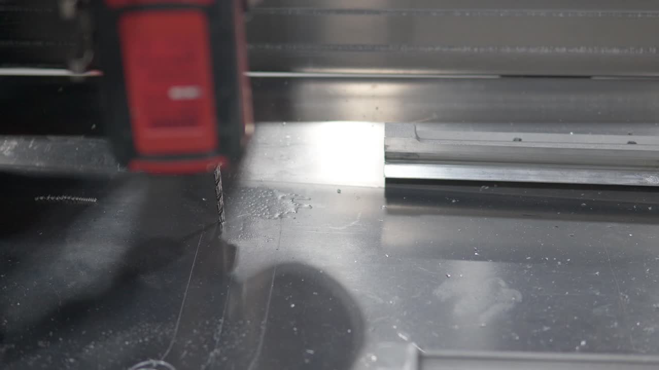 primer plano de las manos del hombre perforando un agujero en una hoja de metal con una herramienta cortadora de sierra perforadora